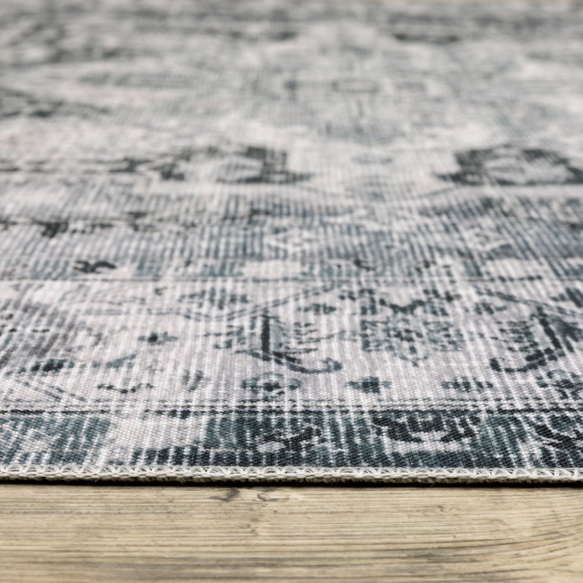 Charleston Charcoal & Ivory Washable Rug with distressed traditional patterns on a wooden floor.