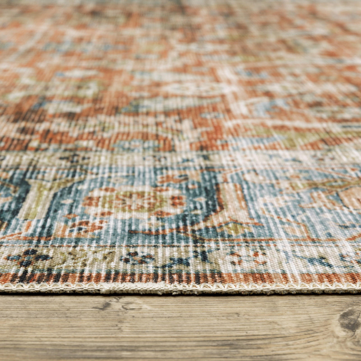 Charleston Rust & Blue washable polyester rug with distressed traditional patterns and blanket stitch finish on wood floor.