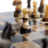 Stylish black and tan horn and resin chess board with a textured checkerboard pattern and pieces.
