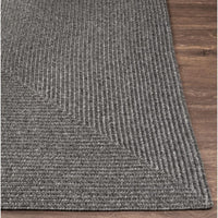 Charcoal gray braided polypropylene outdoor rug with a textured, no-pile surface on a wooden floor.