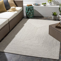 Chesapeake Bay Cream Outdoor Rug, braided polypropylene, no pile, on a patio with wicker furniture.