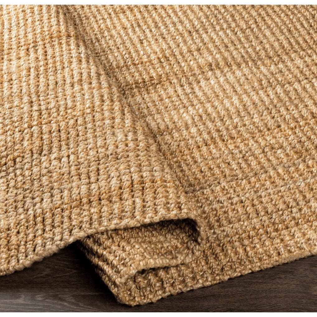 Chunky Naturals light brown hand-woven jute rug with a textured, no-pile design on a dark wood floor.