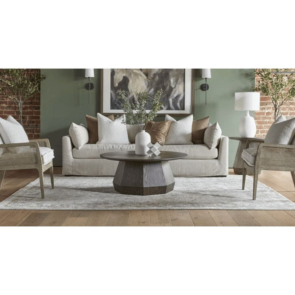 Coulter Burnished Brown Coffee Table: round, dark wood with faceted base, centered in a stylish living room.