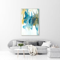 Abstract giclee canvas painting with blue, teal, and gold brushstrokes, framed above a gray sofa.