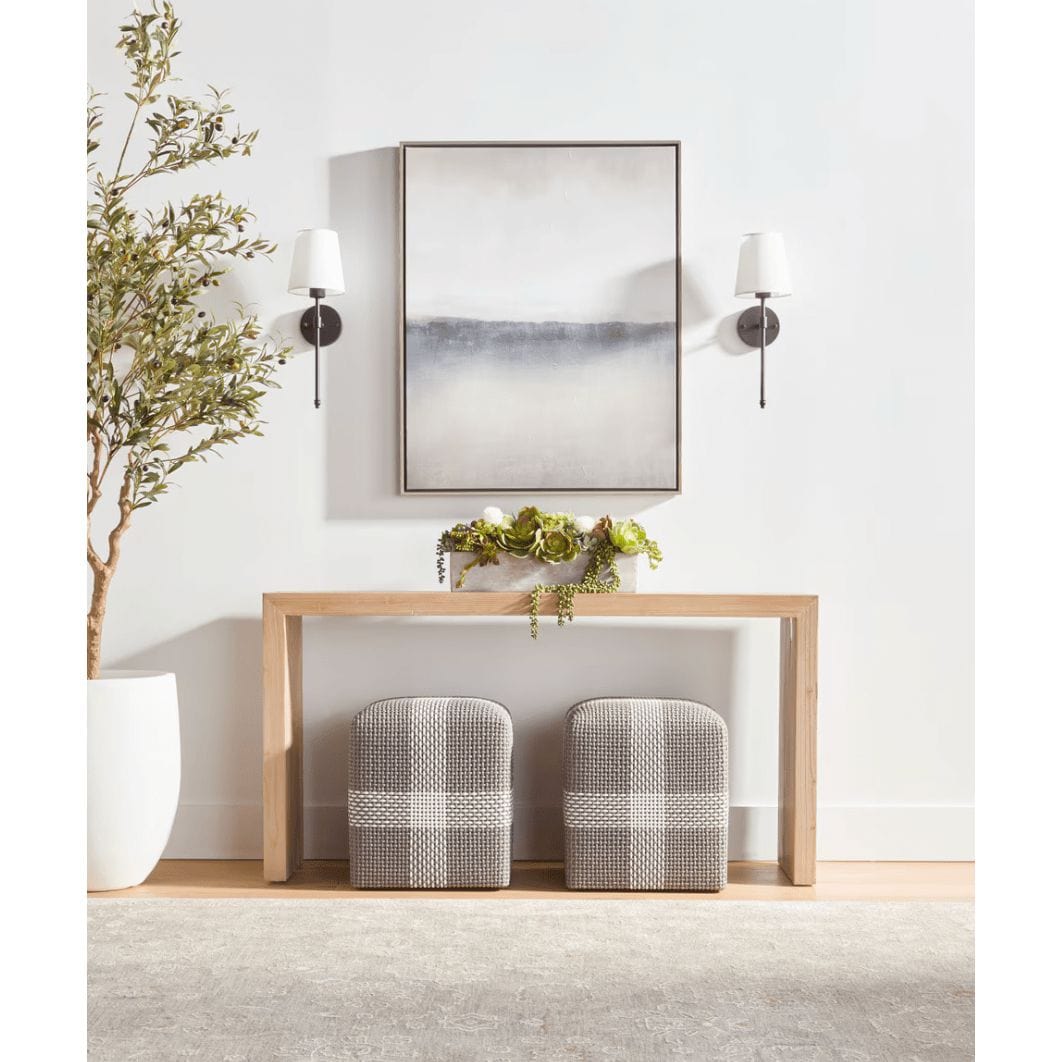 Two gray cross rope ottomans with white accents under a light wood console table.