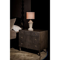 Daryl pale black ribbed mahogany dresser with three drawers and metal pulls, next to a bed.