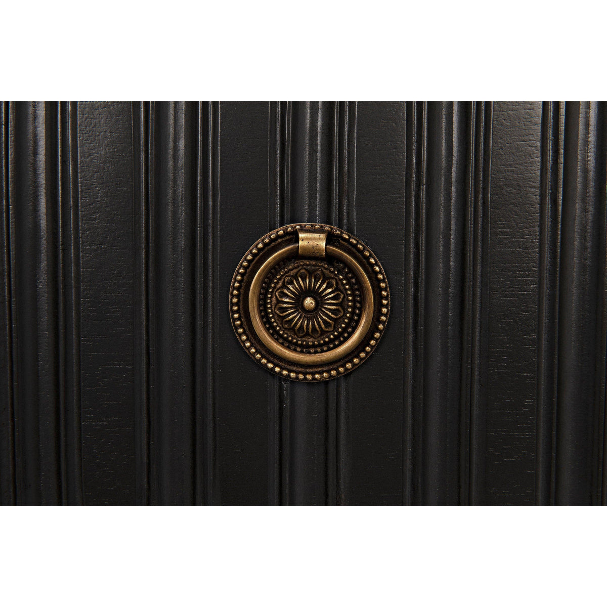 Close-up of a pale black ribbed mahogany dresser with a decorative bronze metal pull.