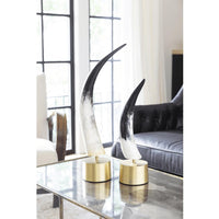 Two black and white natural horn sculptures with matte finish on brass bases, displayed on a glass table.