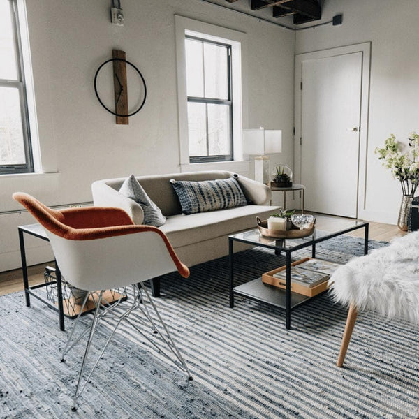 Blue and white striped denim cotton hand-woven rug in a modern living room with a beige sofa and accent chairs.