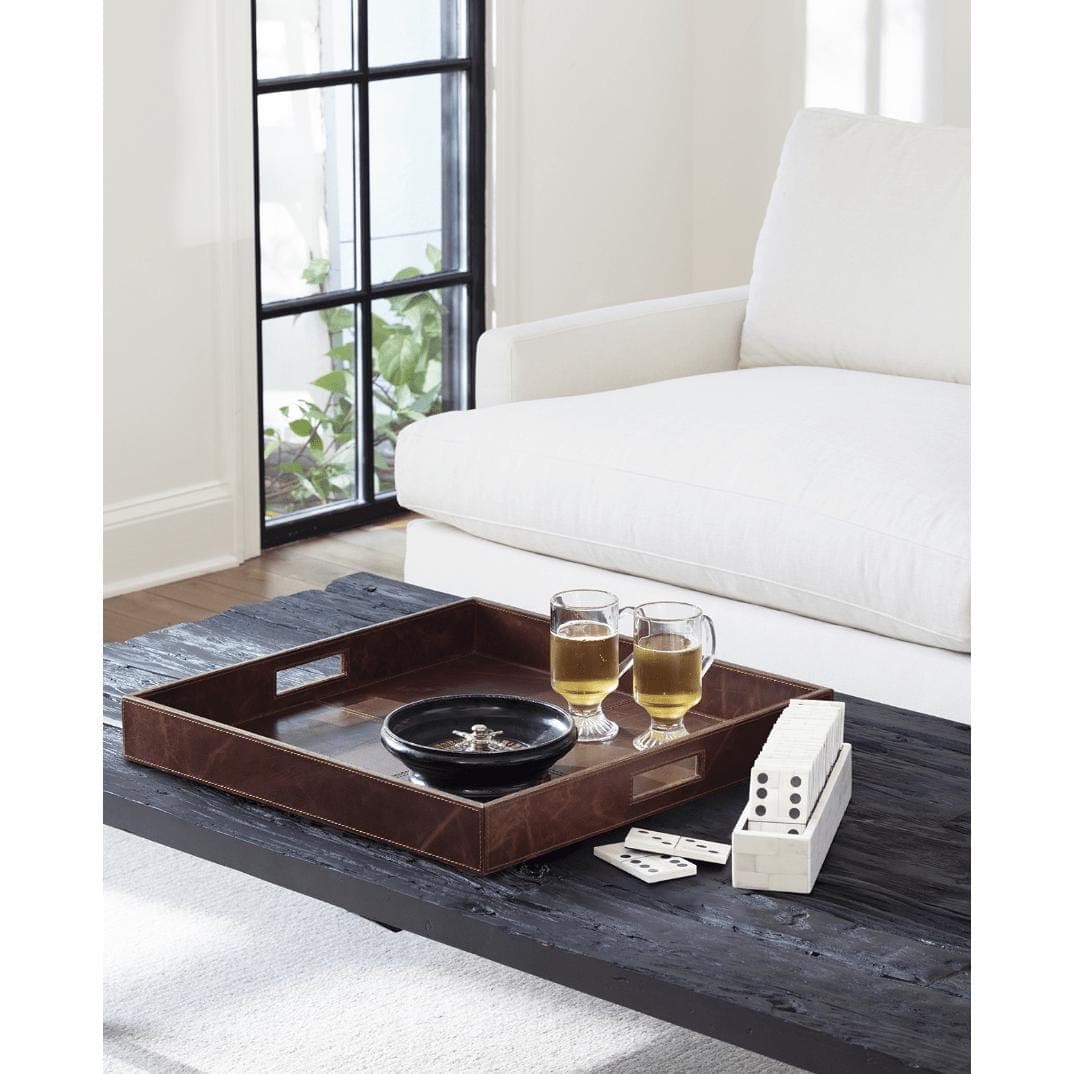 Derby brown square genuine leather tray with built-in handles on a dark wood table, holding drinks and games.