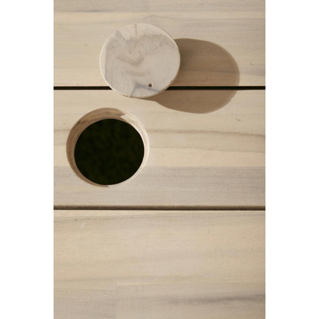 Close-up of Diego Gray Teak Rectangle Dining Table with round umbrella hole and matching wood plug.