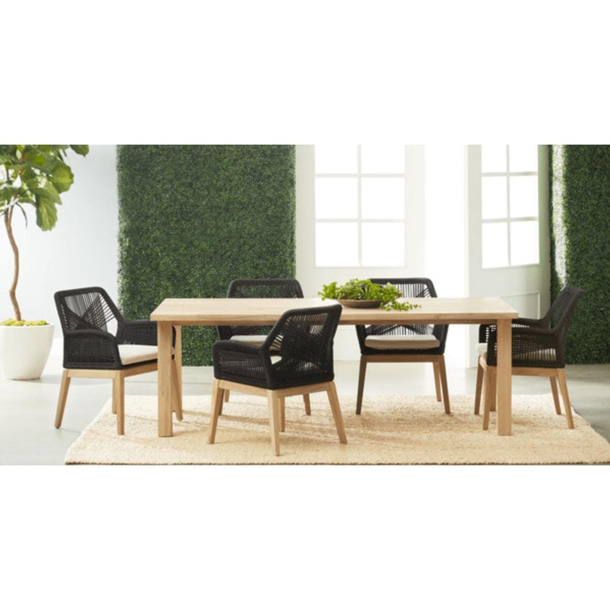 Diego Gray Teak Rectangle Dining Table with natural silver tone finish, surrounded by four black woven chairs.