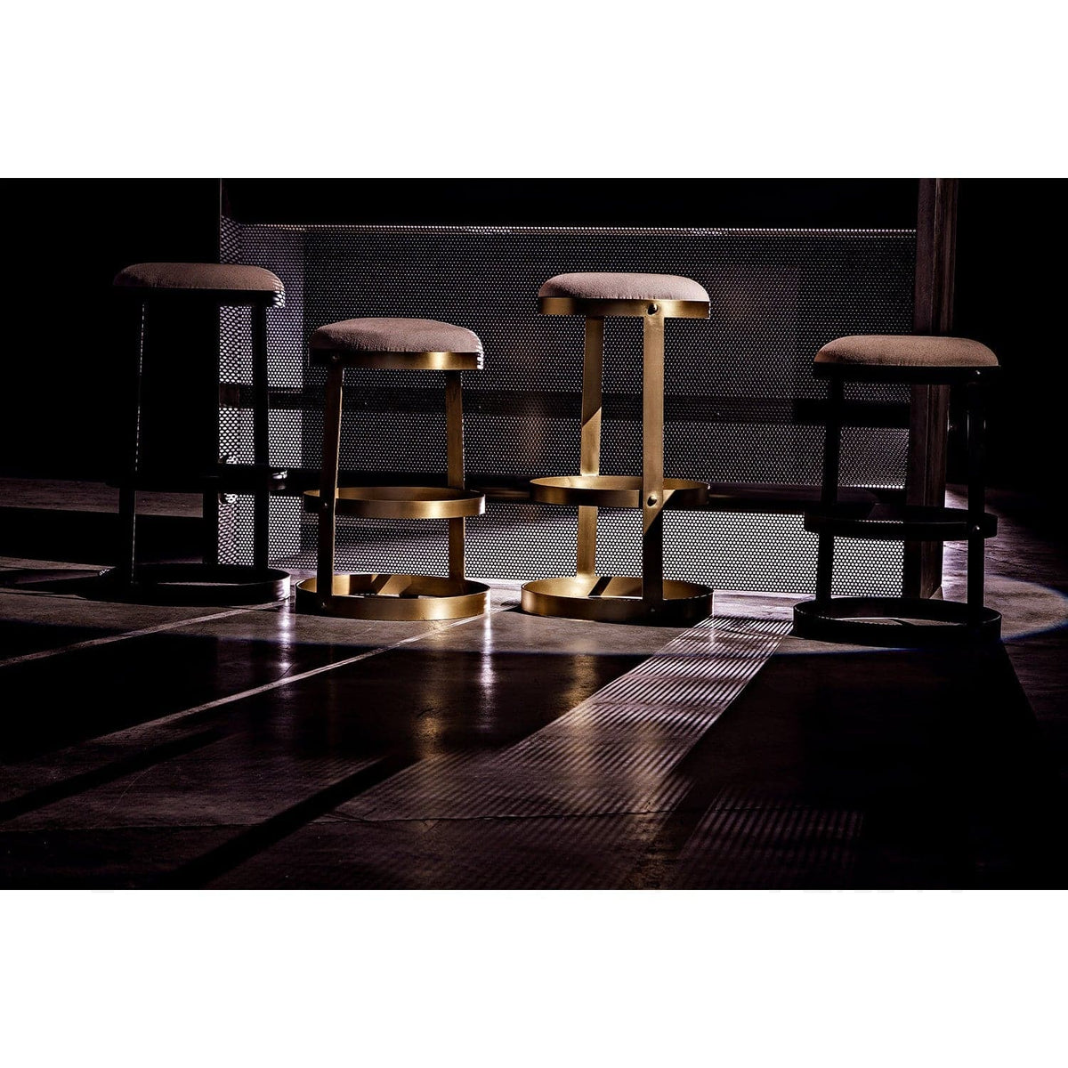 Four Dior Bar Stools with linen seats and circular metal bases in black and antique brass finishes.