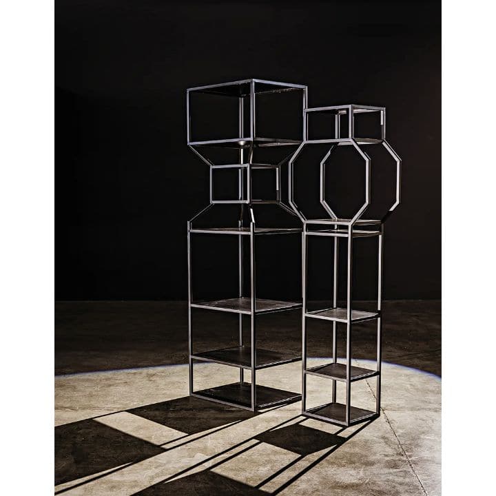 Tall black metal Downtown Bookcase with linear and geometric shelves, casting long shadows.