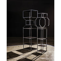 Tall black metal Downtown Bookcase with linear and geometric shelves, casting long shadows.