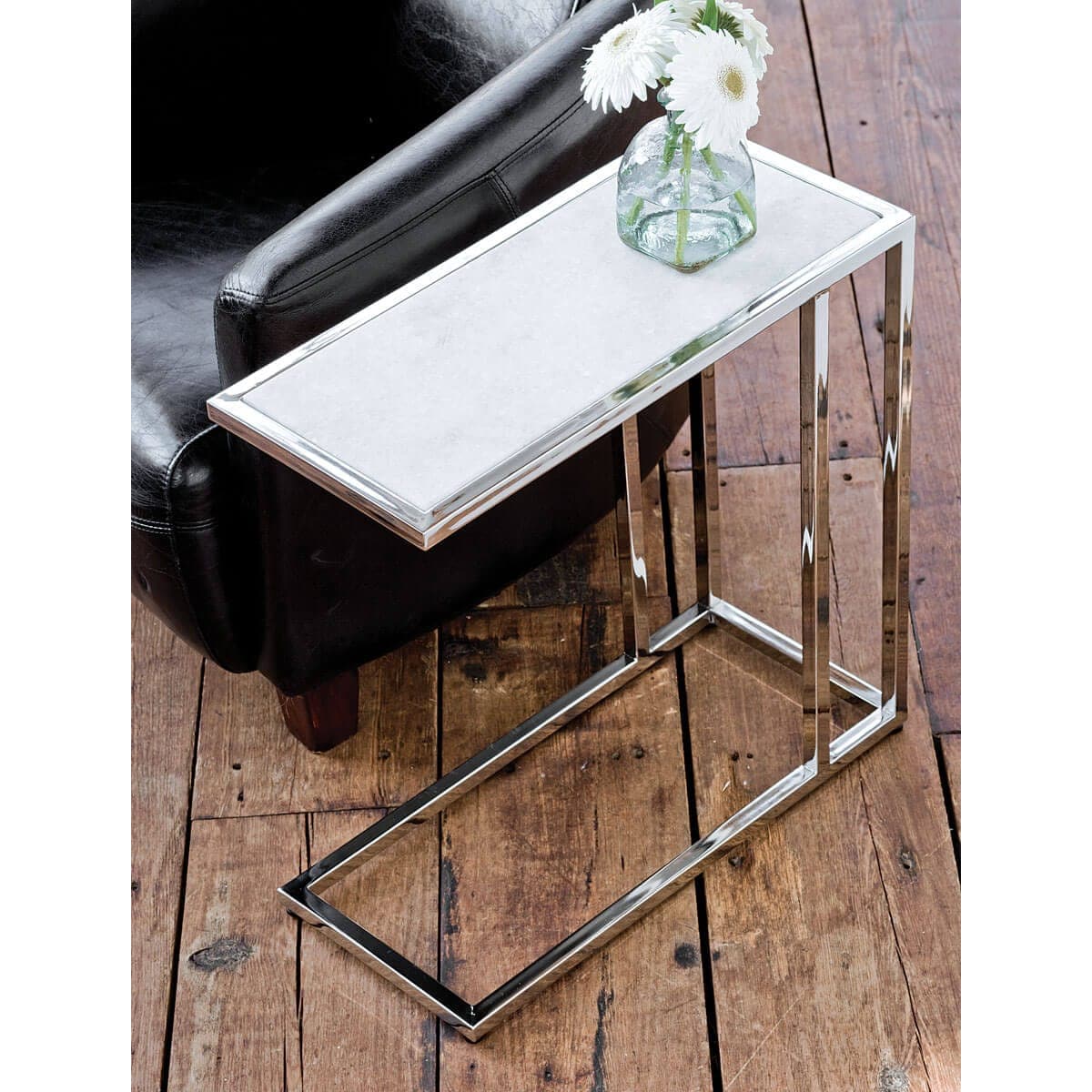 Echelon sofa hugger table with white marble top and polished nickel iron frame, next to a black armchair.