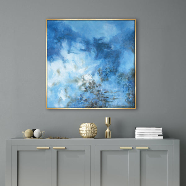 Abstract blue giclee canvas painting with brush gel finish in a gold frame, above a gray console.