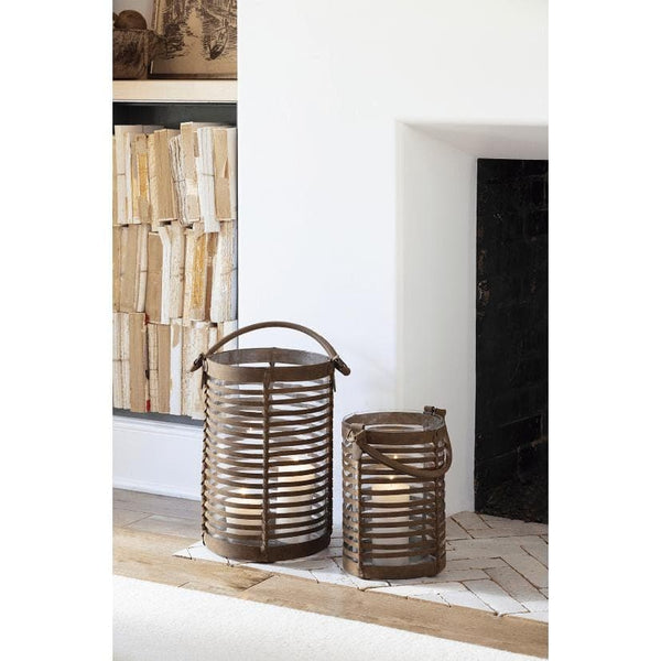 Small Finn woven brown leather hurricane lantern with a candle, next to a larger matching lantern.