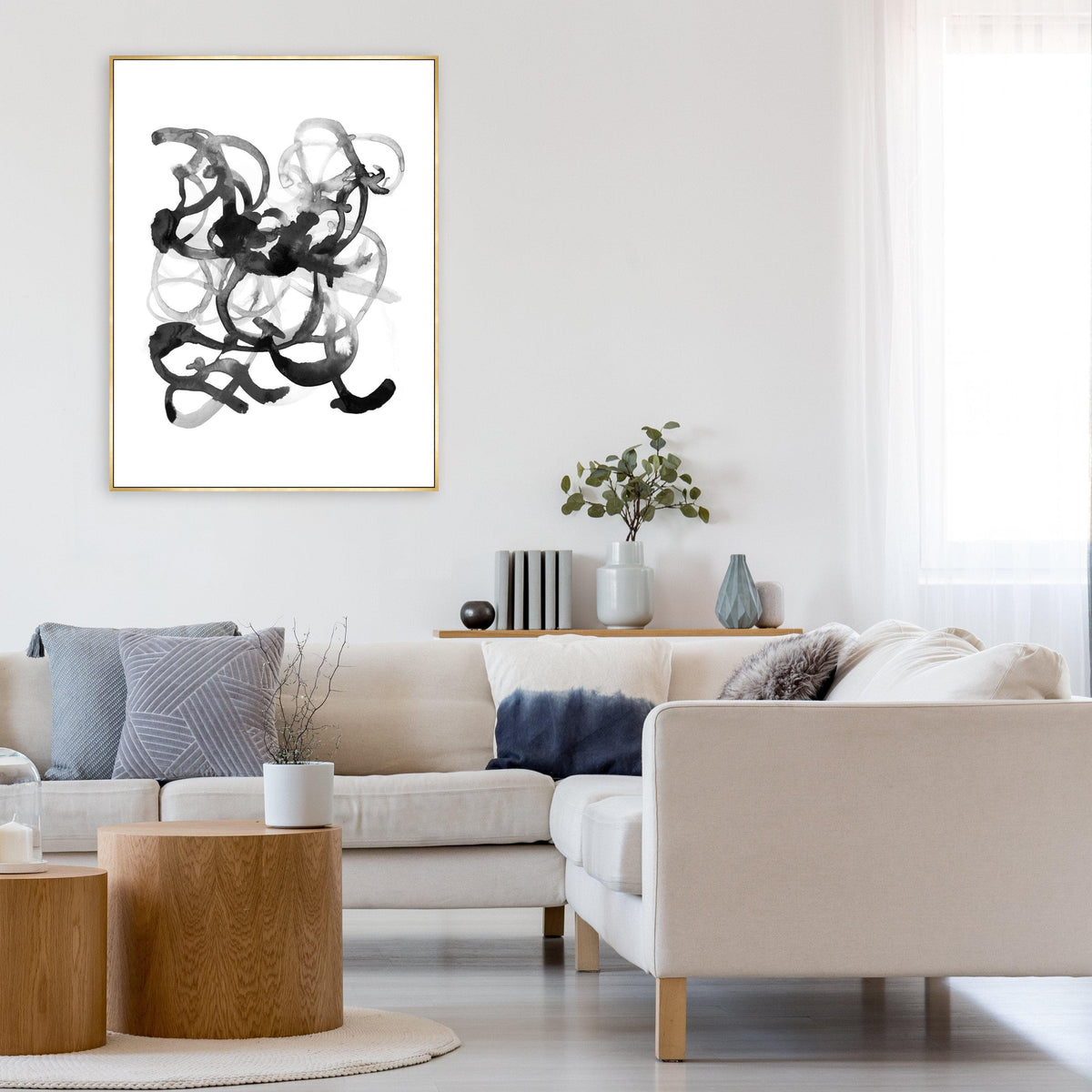 Abstract black and white giclee canvas art with brush gel finish in a gold frame, above a cream sectional.