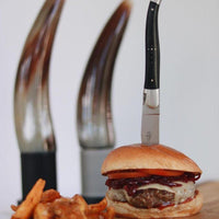 Hamburger with a knife sticking out on a white background