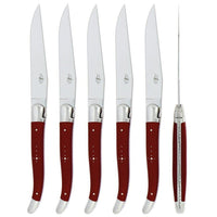 Set of five steak knives with red handles on a white background