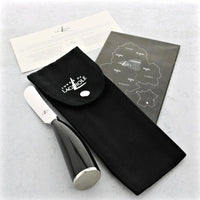 Cheese knife with black handle and silver blade, accompanied by a black pouch and a map on a light gray background.