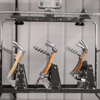 Three corkscrews with wooden handles on a metal stand against a neutral background