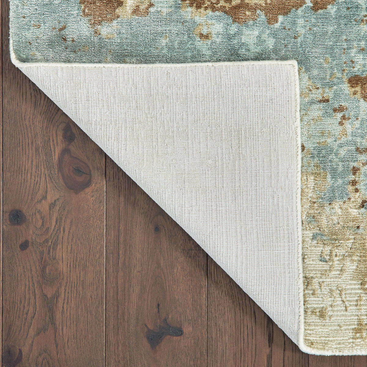 Formations Spa Blue & Brown viscose rug with organic abstract patterns and hand-carved texture, shown flipped on wood floor.