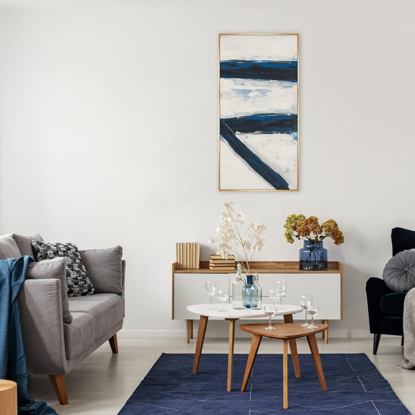 Abstract giclee canvas painting with bold blue and white brushstrokes in a gold frame, styled in a modern living room.