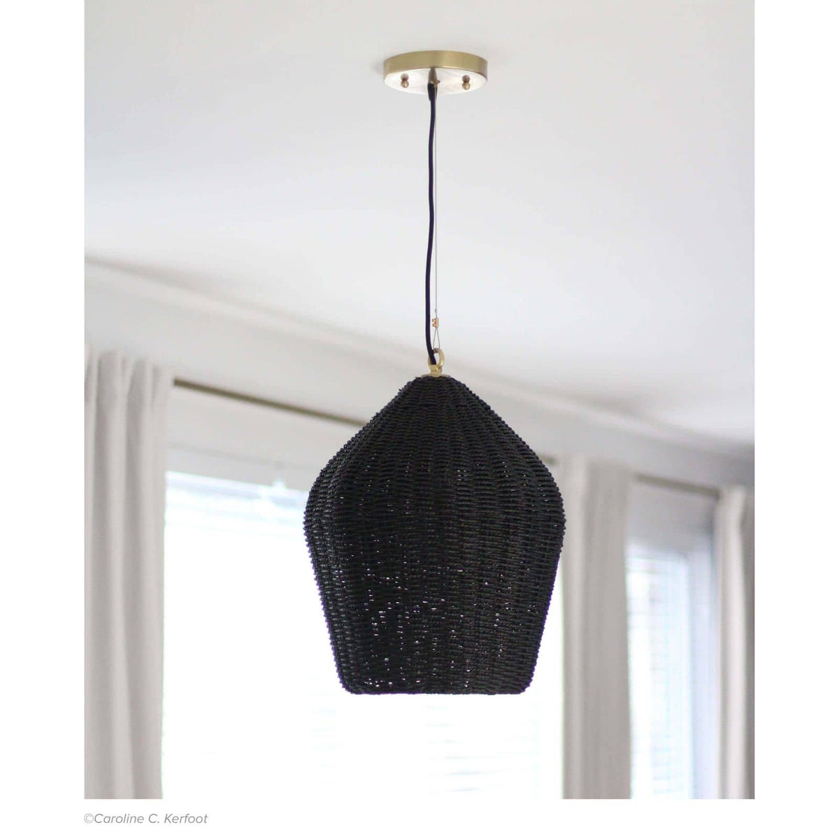Black rattan Georgian pendant light with natural brass accents and black cord, hanging from a white ceiling.