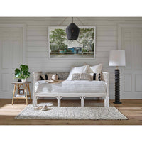 Black rattan Georgian pendant light with natural brass accents, hanging over a daybed in a coastal-style room.
