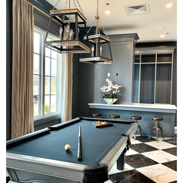 Two Gerome black and aged brass pendant lights illuminate a modern farmhouse game room with a pool table.