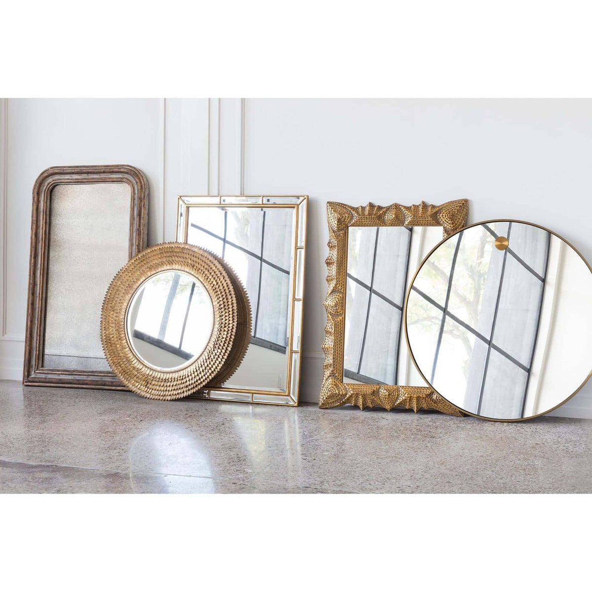Elegant 36" circular mirror with a slender natural brass frame, leaning against a white wall.