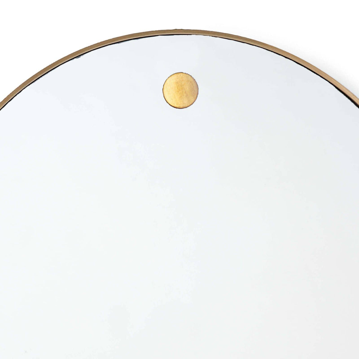 Close-up of a 36" circular mirror with a slender natural brass frame and a visible brass hanging stud.