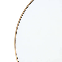 Close-up of a hanging circular mirror with a slender natural brass frame.