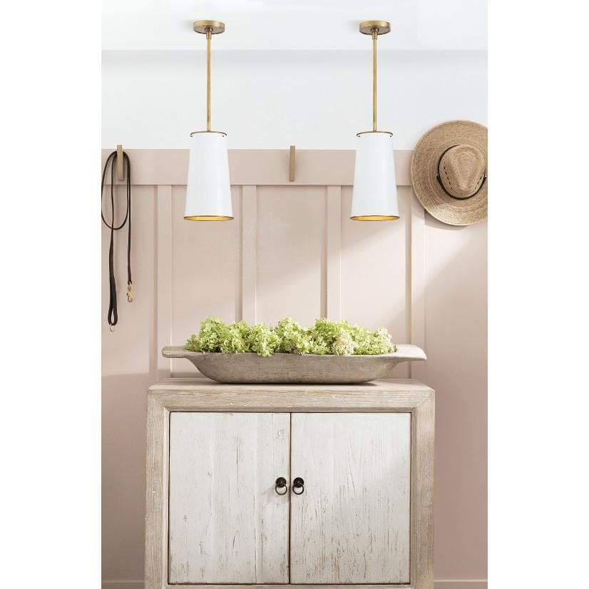 Two Hattie white tapered cylinder pendant lights with natural brass accents hanging above a rustic cabinet.