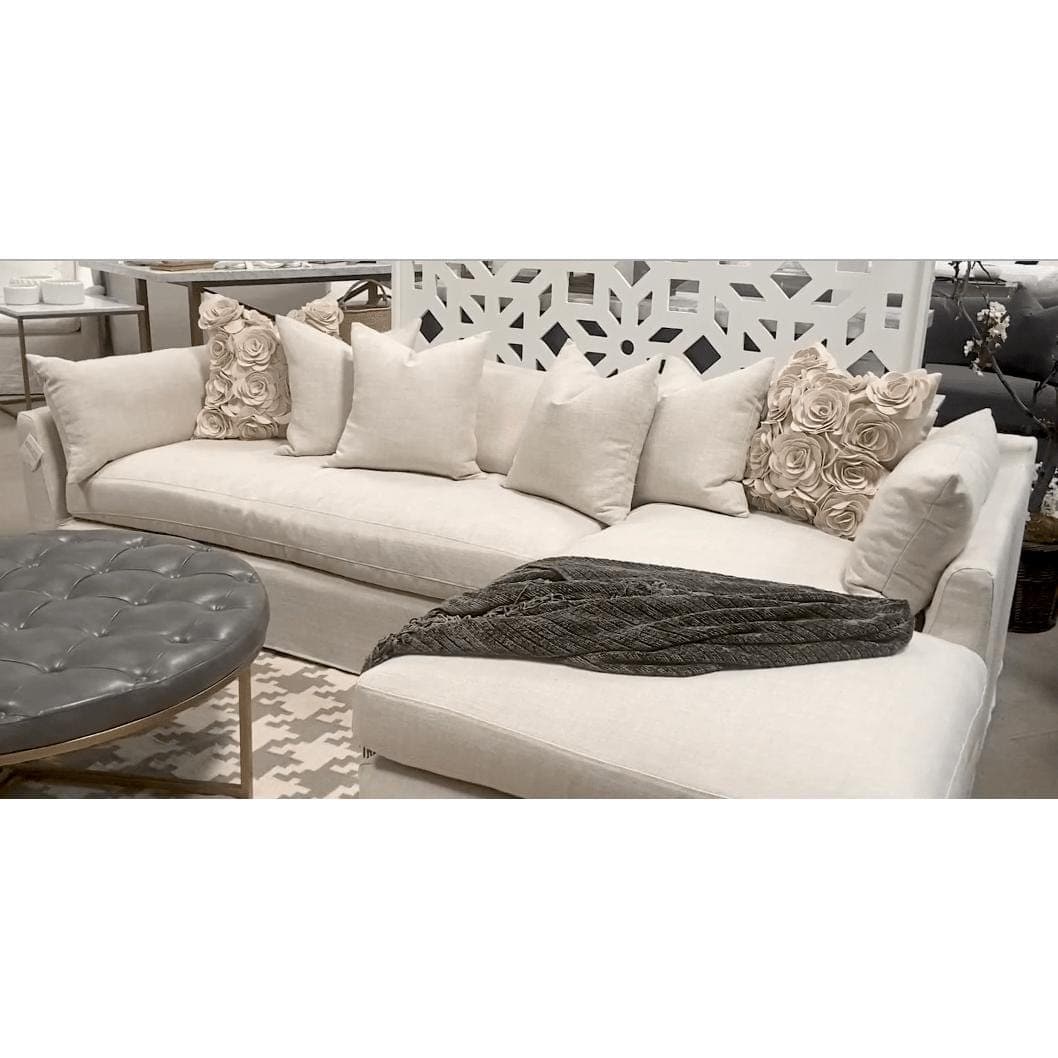 Hayberry slipcover sectional in a linen-polyester blend, light beige with a chaise, throw pillows, and a gray ottoman.
