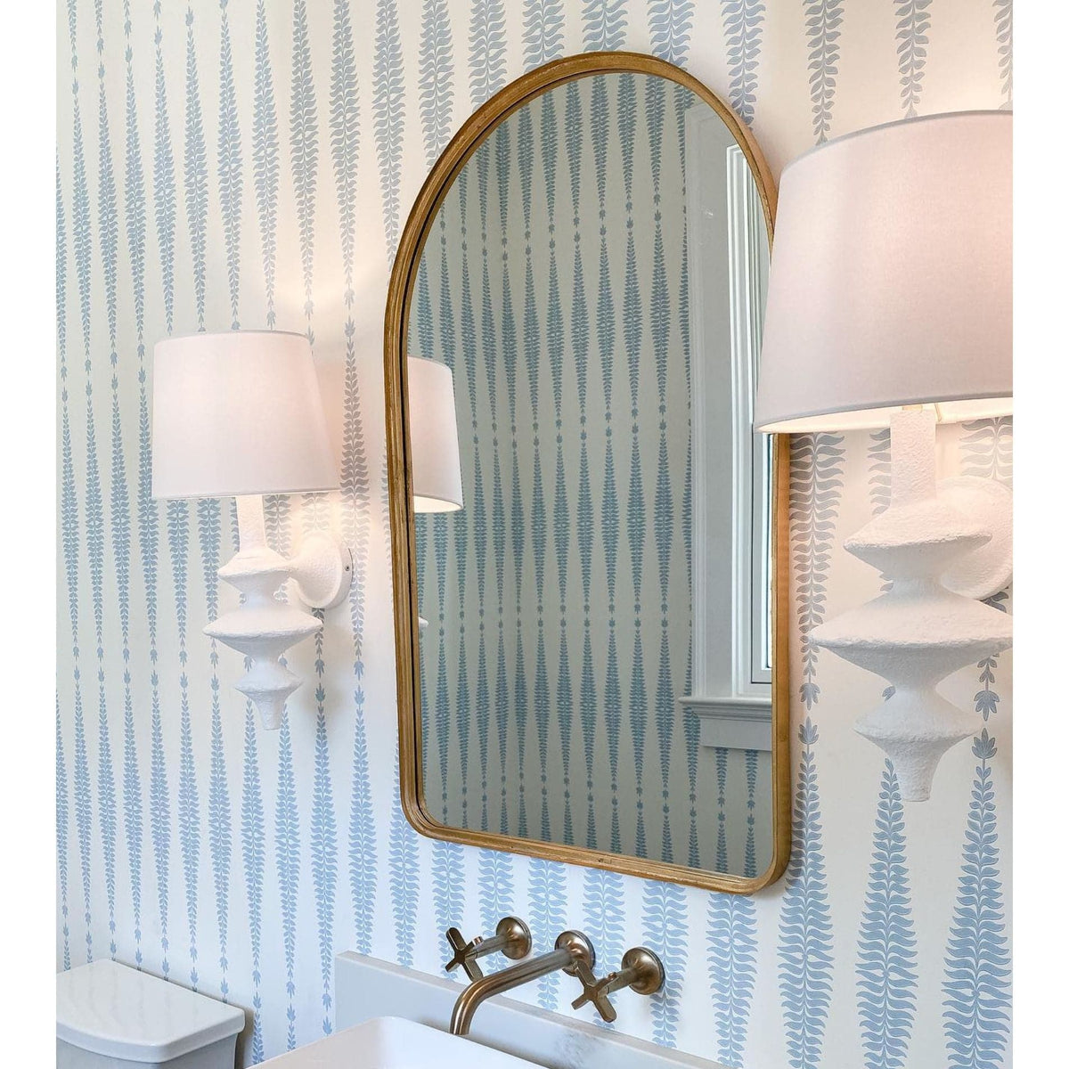 Hope Sculptural Wall Sconce with complex curves, matte white finish, and linen shade, flanking a gold mirror.