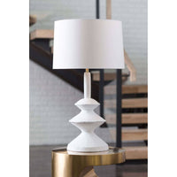 Hope Table Lamp: Matte white paper mache base with complex curves, linen shade, on a brass table.