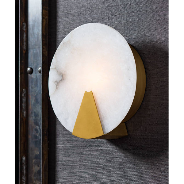 Round Houston sconce with natural alabaster diffuser and brass framing, mounted on a dark textured wall.