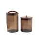Two brown glass canisters with wooden lids on a white background