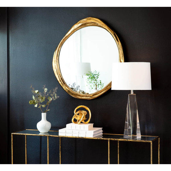 Ibiza Mirror with organic antique gold frame, reflecting a room, above a console table.