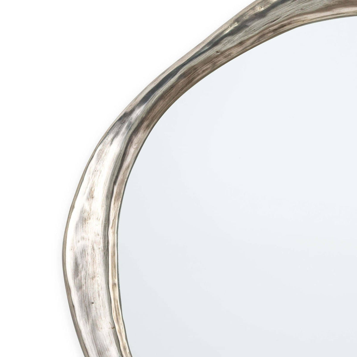 Ibiza Mirror with an organic, undulating antique silver frame and warm ambered glow.