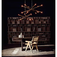Ikram small metal brass finish chandelier with antique glow over a wooden desk and bookshelf.
