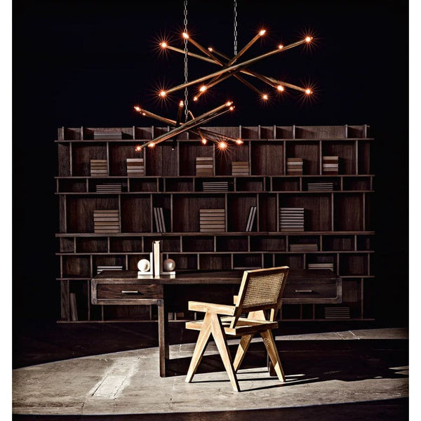 Ikram small metal brass finish chandelier with antique glow over a wooden desk and bookshelf.