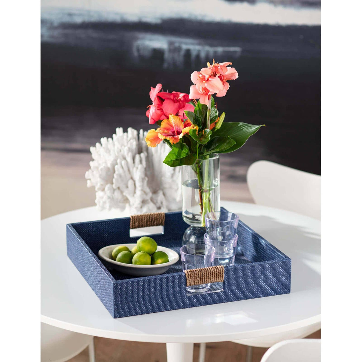 Indigo large square decorative tray with rope-wrapped handles, holding limes, glasses, and a vase of flowers.