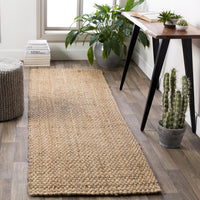 Tan hand-woven jute runner rug on a wooden floor, adding natural charm to a room.