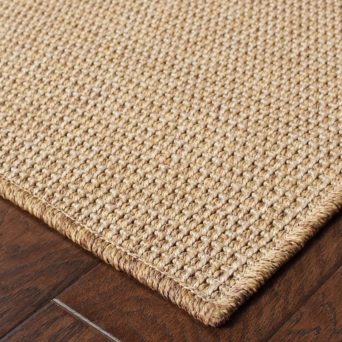 Karavia Sand outdoor rug, a durable, machine-woven polypropylene rug with a natural seagrass look on wood floor.