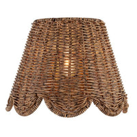 Kismet Sconce with a woven rattan-like shade and a scalloped bottom edge, emitting a warm glow.
