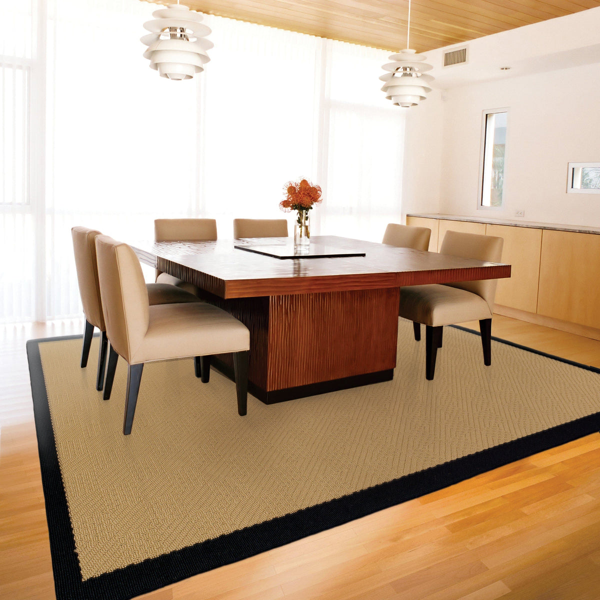 Lanai Beige & Black Outdoor Rug with natural Sisal-inspired weave under a modern dining table.